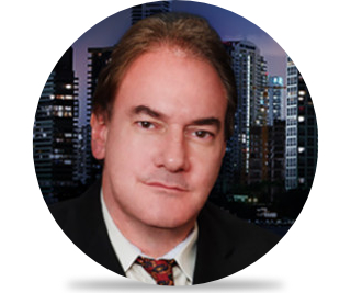 A man in suit and tie with buildings behind him.