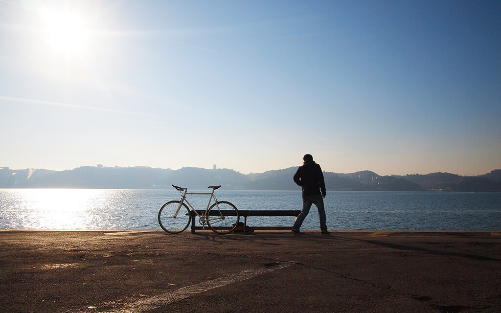 A man standing next to a bench with his bike on it.